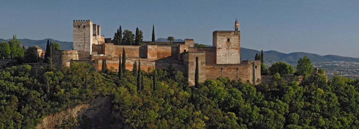 Sunlit ramparts of the Alcazaba fortress at the Alhambra with visitors below, Granada